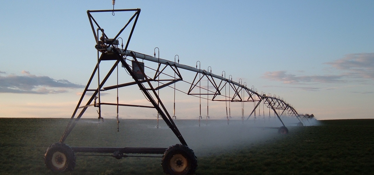 Center pivot irrigation system watering a field at dusk